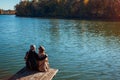 Senior family couple relaxing by autumn lake. Happy man and woman enjoying nature and hugging sitting on pier Royalty Free Stock Photo