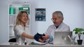 Senior family doctor measures blood pressure with a tonometer to woman patient and speaking to her during consultation