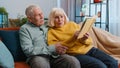 Senior family couple man woman enjoying reading interesting book, talking, laughing at home on sofa Royalty Free Stock Photo