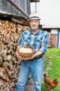 Portrait of senior farmer carrying fresh eggs in basket at barn Royalty Free Stock Photo