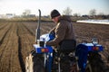 Senior farmer cultivating the farm field on a tractor. Seasonal worker. Recruiting workers for work on agricultural machinery.