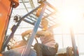 Senior farmer driving forklift in greenhouse with yellow lens flare in background Royalty Free Stock Photo