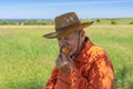 Senior farmer eating handmade patty under tree shadow near his field