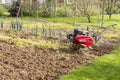Senior farmer gardener working in the garden with rototiller , tiller tractor, cutivator, miiling machine Royalty Free Stock Photo
