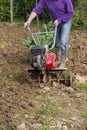 Senior farmer gardener working in the garden with rototiller , tiller tractor, cutivator, miiling machine Royalty Free Stock Photo