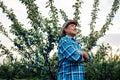 Senior farmer with hat standing in plum orchard,