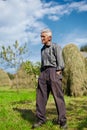Senior farmer on a meadow with hay stacks Royalty Free Stock Photo