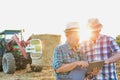 Close up of senior farmer using digital tablet with mature farmer standing against tractor in field Royalty Free Stock Photo