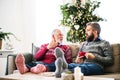 A senior father and adult son sitting on a sofa at home at Christmas time, talking. Royalty Free Stock Photo