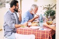 Senior father and adult son having lunch together at home in outdoor terrace having fun with love and friendship - festive and Royalty Free Stock Photo