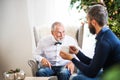 A senior father and adult son sitting on a sofa at Christmas time, talking. Royalty Free Stock Photo