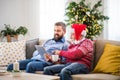 A senior father and adult son with tablet sitting on a sofa at home at Christmas time. Royalty Free Stock Photo