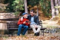 Senior father and his son sitting on bench by lake in nature, using tablet. Royalty Free Stock Photo