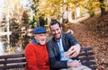 Senior father and his son sitting on bench in nature, taking selfie.