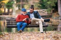 Senior father and his son sitting on bench in nature, using tablet. Royalty Free Stock Photo