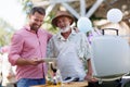 Senior father and son grilling together at a garden bbq party. Royalty Free Stock Photo