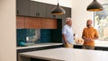 Senior Father Talking And Drinking Coffee With Adult Son In Kitchen At Home Royalty Free Stock Photo