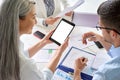 Senior female business leader holding tablet with colleagues in office at desk. Royalty Free Stock Photo