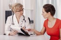 Female doctor showing medical records to her young beautiful patient