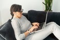 Charming modern senior woman using laptop sitting on comfortable couch Royalty Free Stock Photo