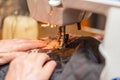 Senior female hands stitching fabric on sewing machine.