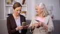 Senior female holding dollars complaining friend on poverty problem, low income