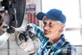 Senior female mechanic repairing a car in a garage. Royalty Free Stock Photo