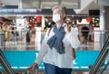 Senior female traveler in airport dutyfree area with luggages waiting for departure of flight. Coronavirus and freedom concept Royalty Free Stock Photo