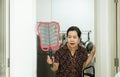 Senior woman using mosquito swatter at home,Female with mosquito electric net racket in bedroom Royalty Free Stock Photo