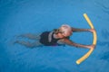 Senior female woman holds on to a flotation device on a swimming pool to learn how to swim Royalty Free Stock Photo