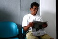 Senior Filipino man read newspaper while at waiting area