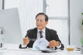 Senior financial asian businessman sitting at his workstation in