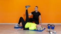 Senior fit woman doing stretching workout exercise standing at the gym isolated on orange background with pesonal trainer. mature Royalty Free Stock Photo