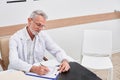 Senior focused doctor writing prescriptions while sitting at his office