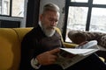 Senior focused man read newspaper on sofa at home Royalty Free Stock Photo