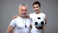 Senior football coach smiling hugging teen boy, active healthy lifestyle, sports