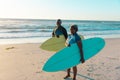 Senior frican american couple with surfboards standing at sandy beach against sea and sky Royalty Free Stock Photo