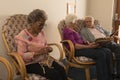 Senior friends knitting and looking photo album at nursing home Royalty Free Stock Photo