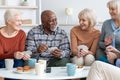 Senior friends playing cards while drinking tea at home Royalty Free Stock Photo