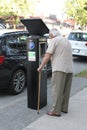 Senior gentleman with a cane, paying for the parking