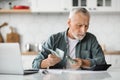 Senior Gentleman Planning Budget, Counting Money And Using Calculator In Kitchen Royalty Free Stock Photo