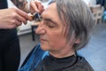 Senior gets eyebrows done in a hairdressing salon