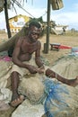 Senior Ghanaian fisherman sits to repair fishnet