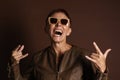 Senior ginger woman with short hair screaming and showing rock gesture with both hands