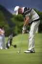 Senior golf player putting at hole.