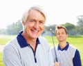 Senior golfer. Closeup of senior golfer smiling and looking at you with son in background. Royalty Free Stock Photo