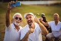 Senior golfers using phone and taking self portrait. Royalty Free Stock Photo