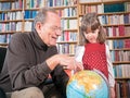 Senior and granddaughter looking at a globe