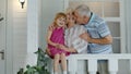 Senior grandfather and child girl embracing grandmother and making a kiss in porch at home Royalty Free Stock Photo