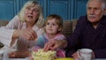 Senior grandfather and grandmother happy laughing, eating popcorn, watching cartoons movies at home Royalty Free Stock Photo